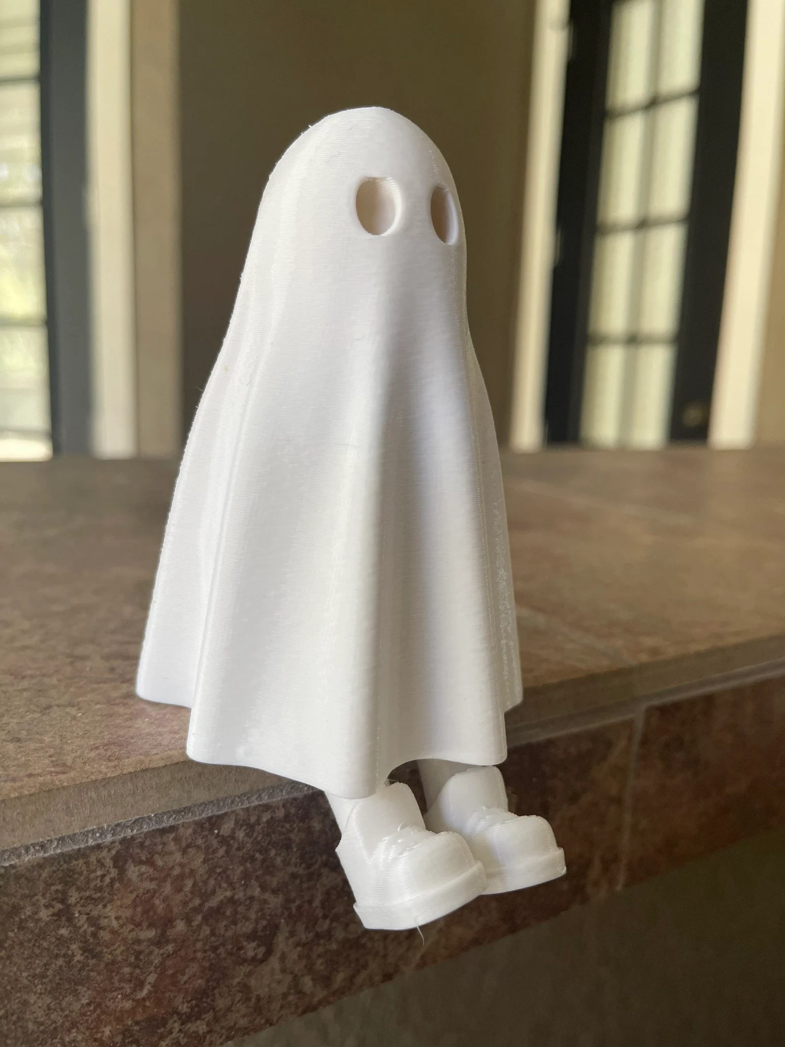 White ghost with hidden legs sitting on the edge of a ledge, legs dangling