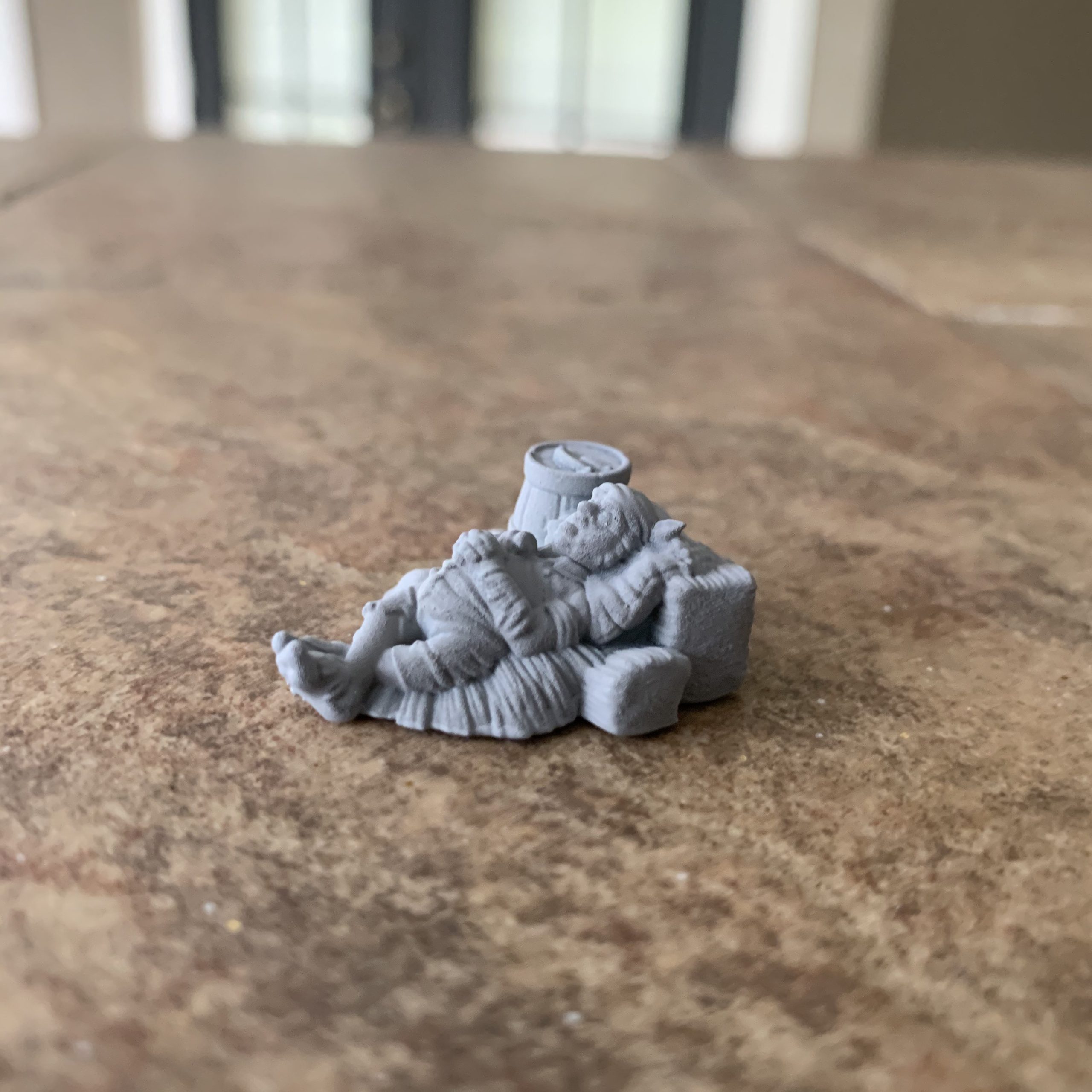 Sleeping halfling guard miniature leaning back against a hay bale, primed gray