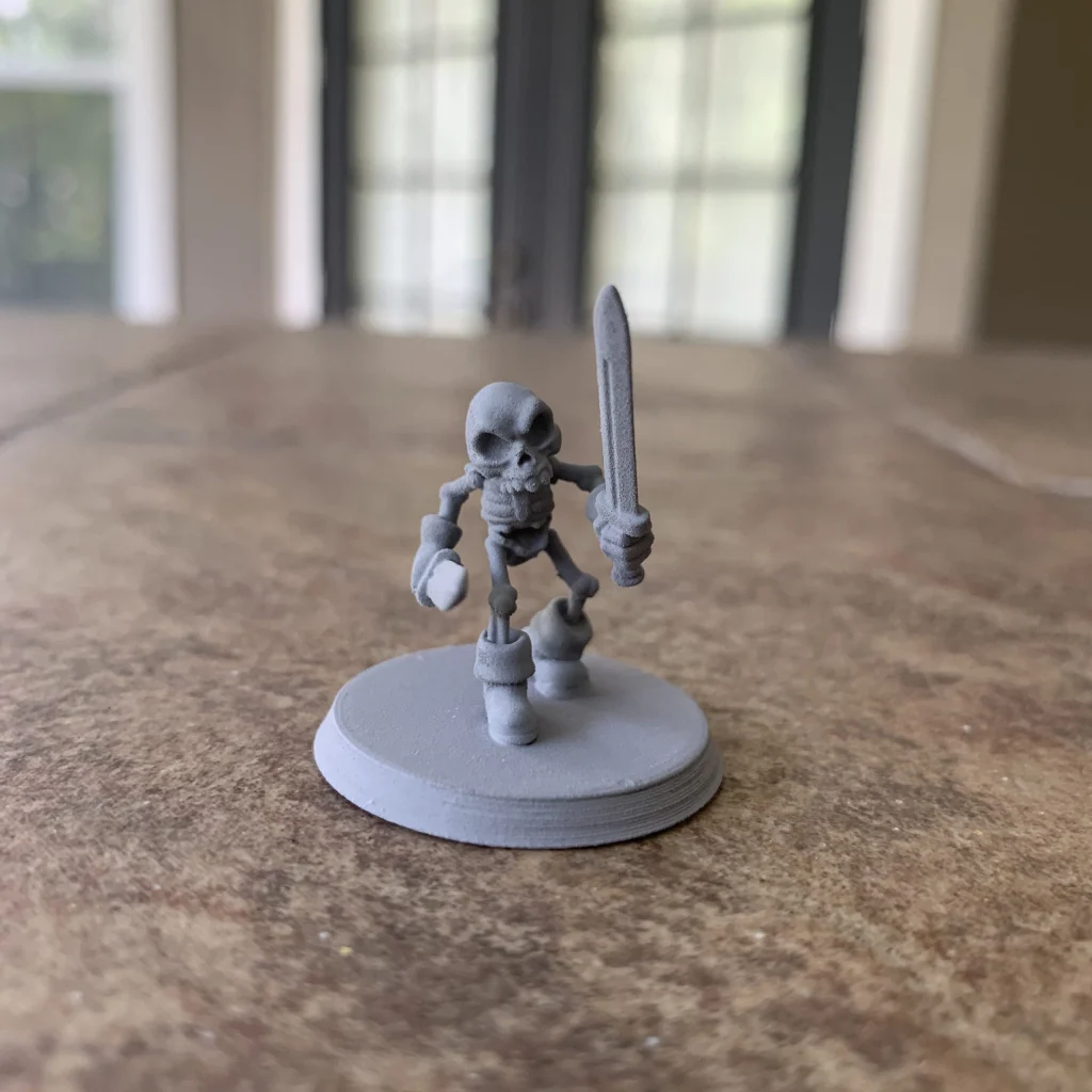 Wee skeleton miniature with a sword and shield, primed gray