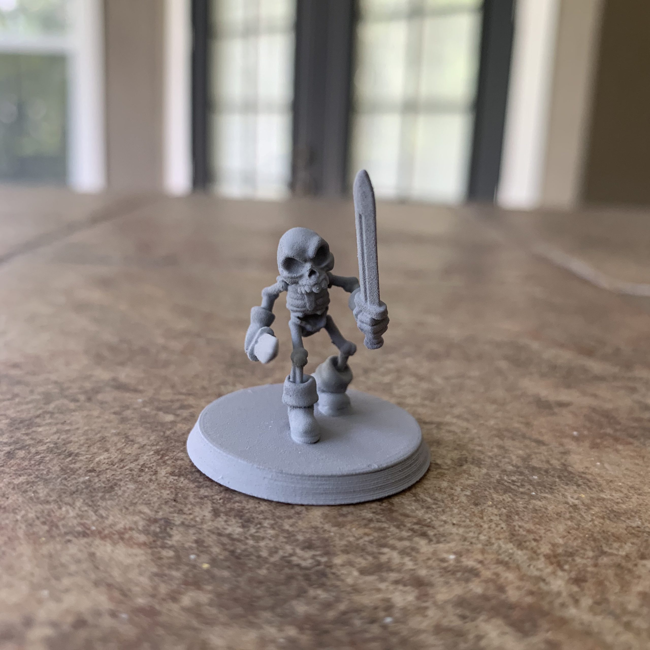 Wee skeleton miniature with a sword and shield, primed gray