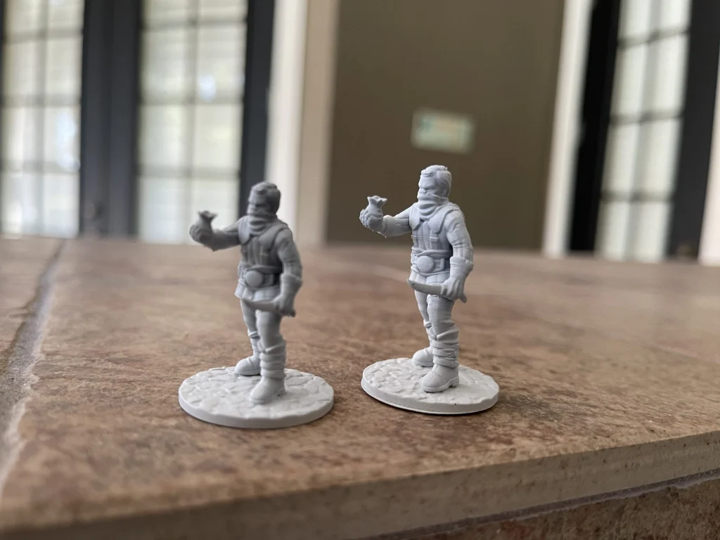 Two bandit miniatures, primed gray, side by side