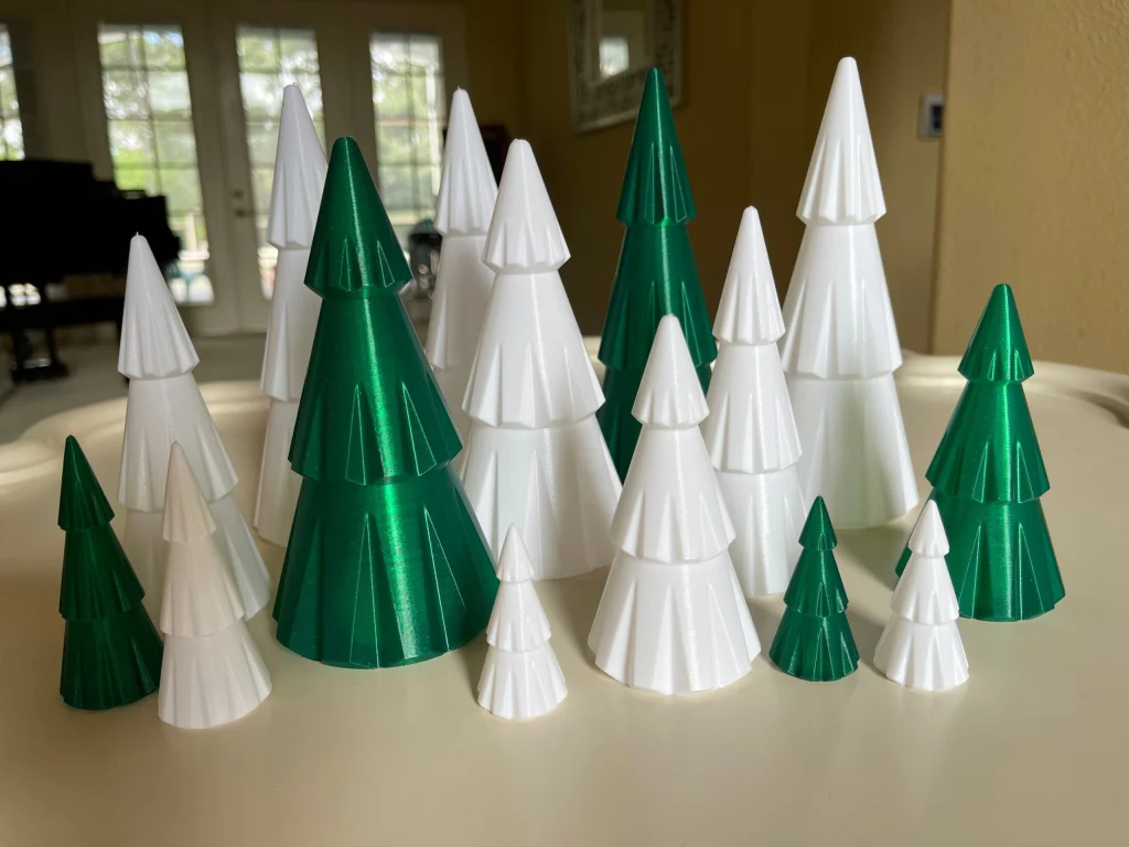 Pointed and non-pointed hollow Christmas trees in white and green, grouped in different heights on a table