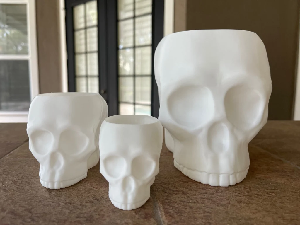 Three white skull holders in small, large and extra-large sizes