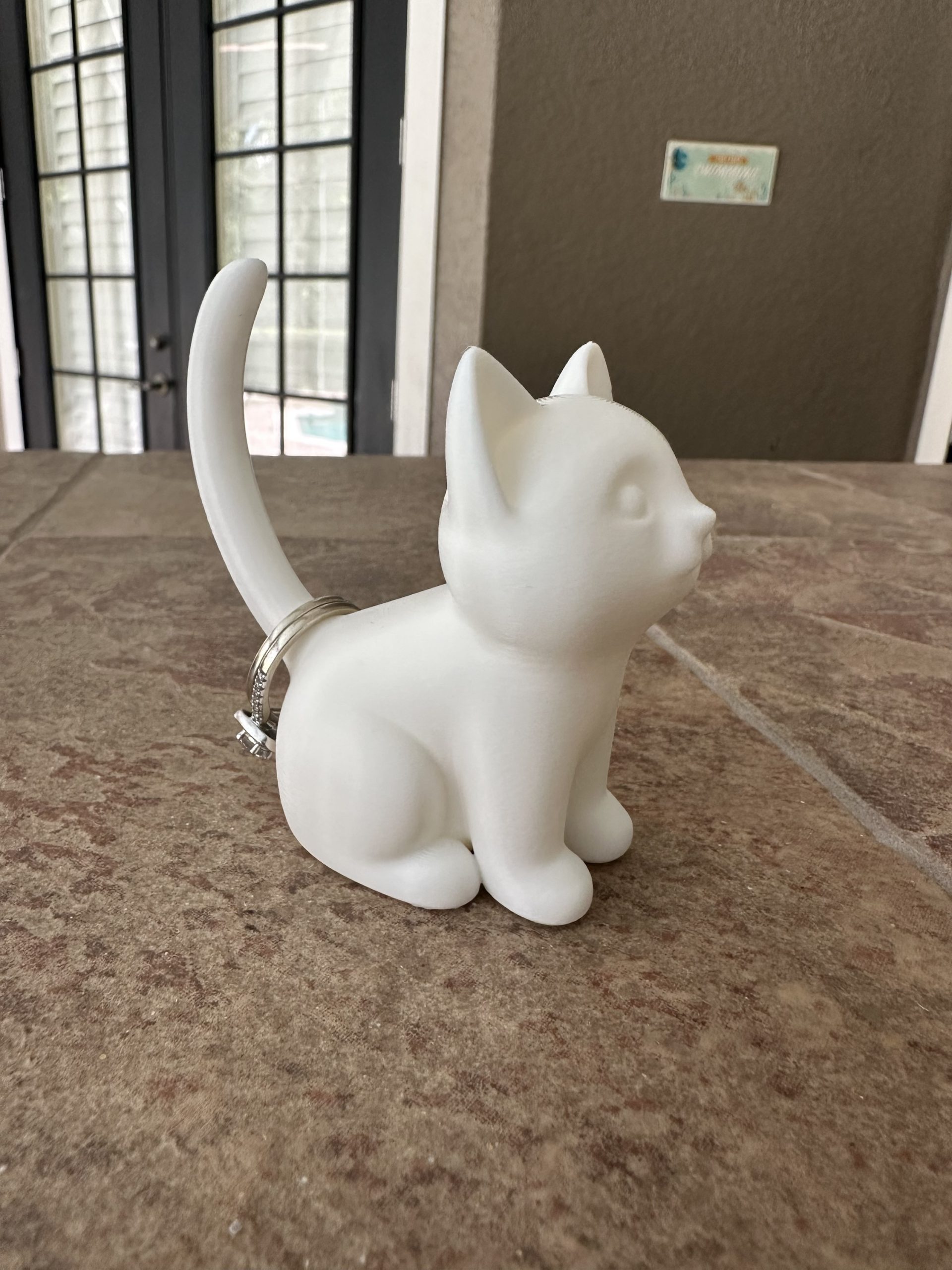 White cat ring holder with a ring on its tail
