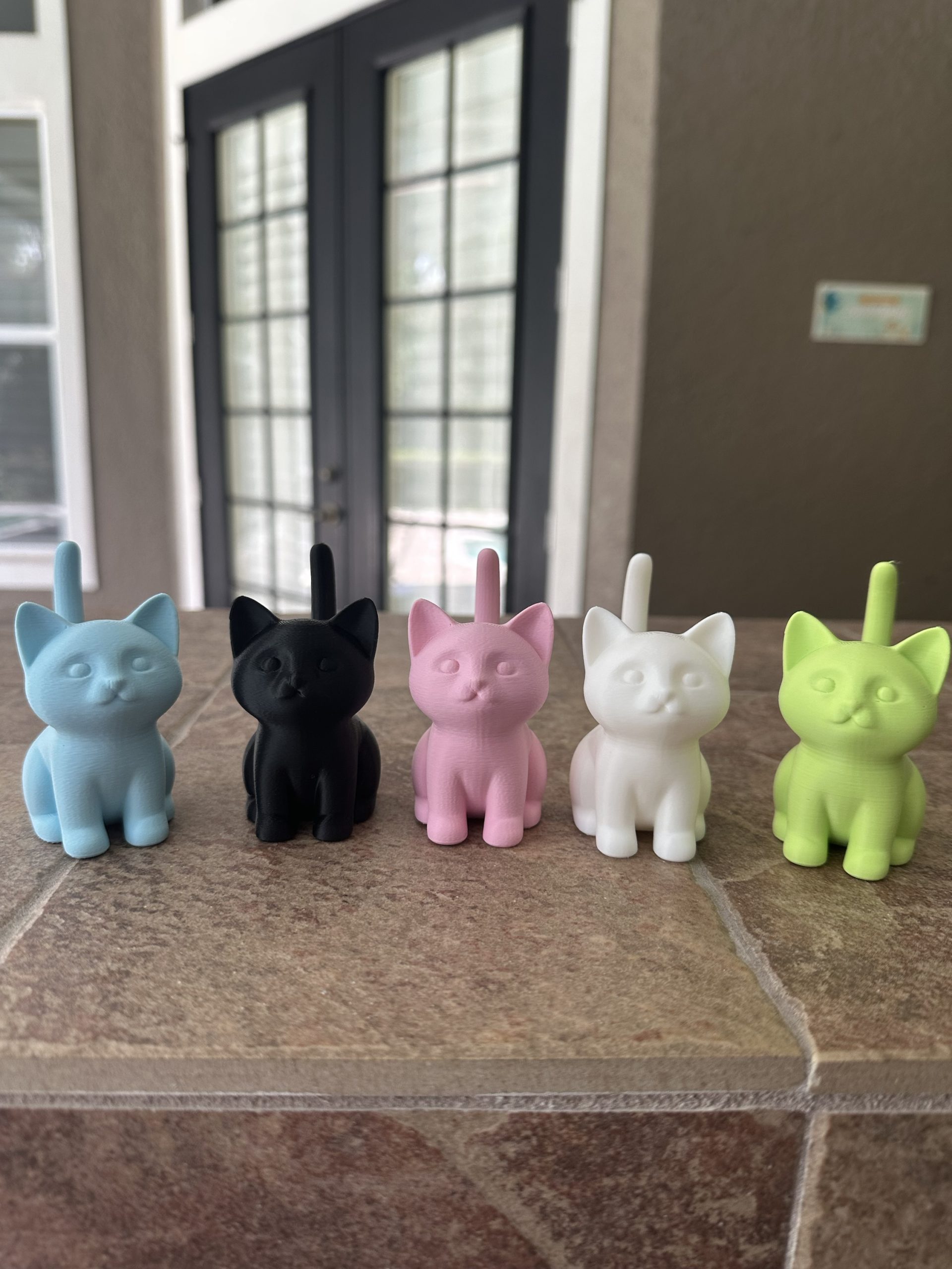 Cat ring holders in light blue, black, light pink, white and light green, side by side