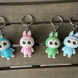 Doll keychains in teal, light pink, mint green and light blue, hanging in a row
