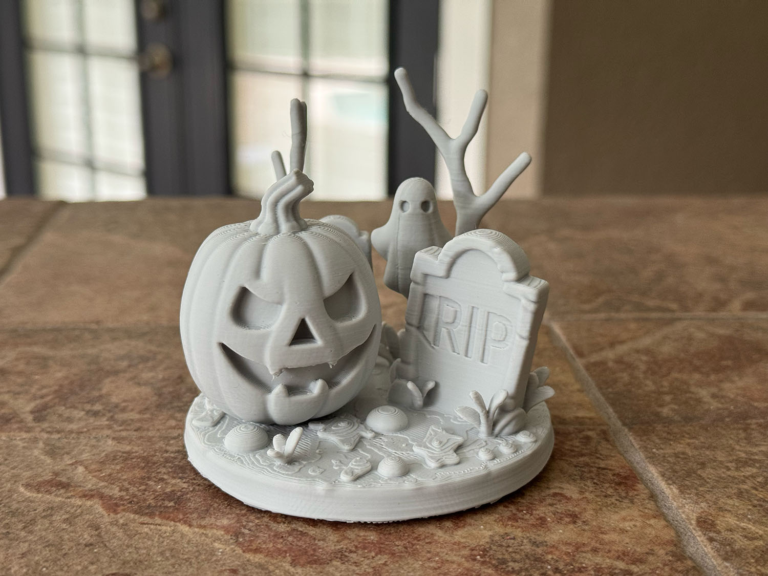 Unpainted light gray pumpkin scene sculpture with a jack-o’-lantern, a ghost and an RIP gravestone